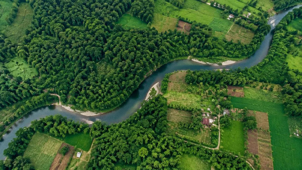 Aerial view of a river winding through forest and small farms